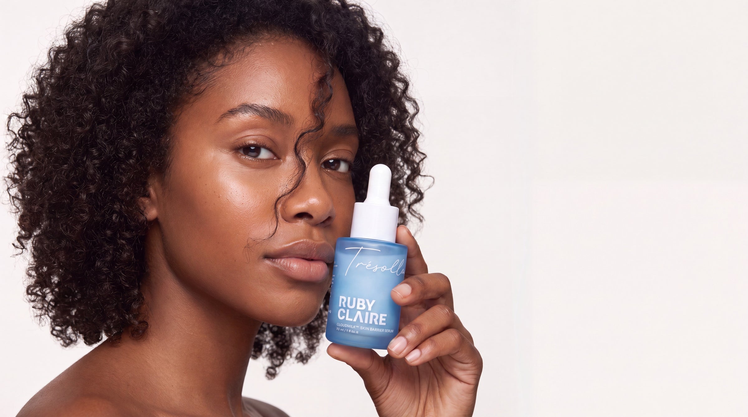 A woman holding a Ruby Claire CloudMilk serum bottle